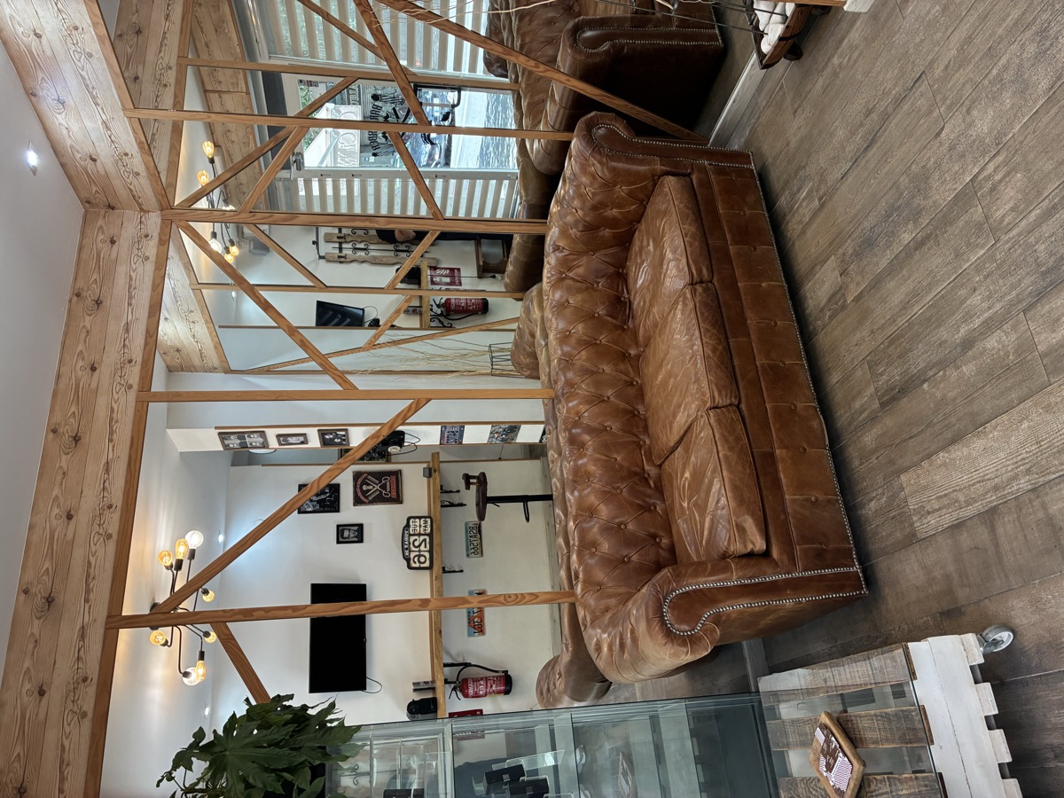 Zona de espera con sofá Chesterfield de cuero en barbería The Barber House Barcelona