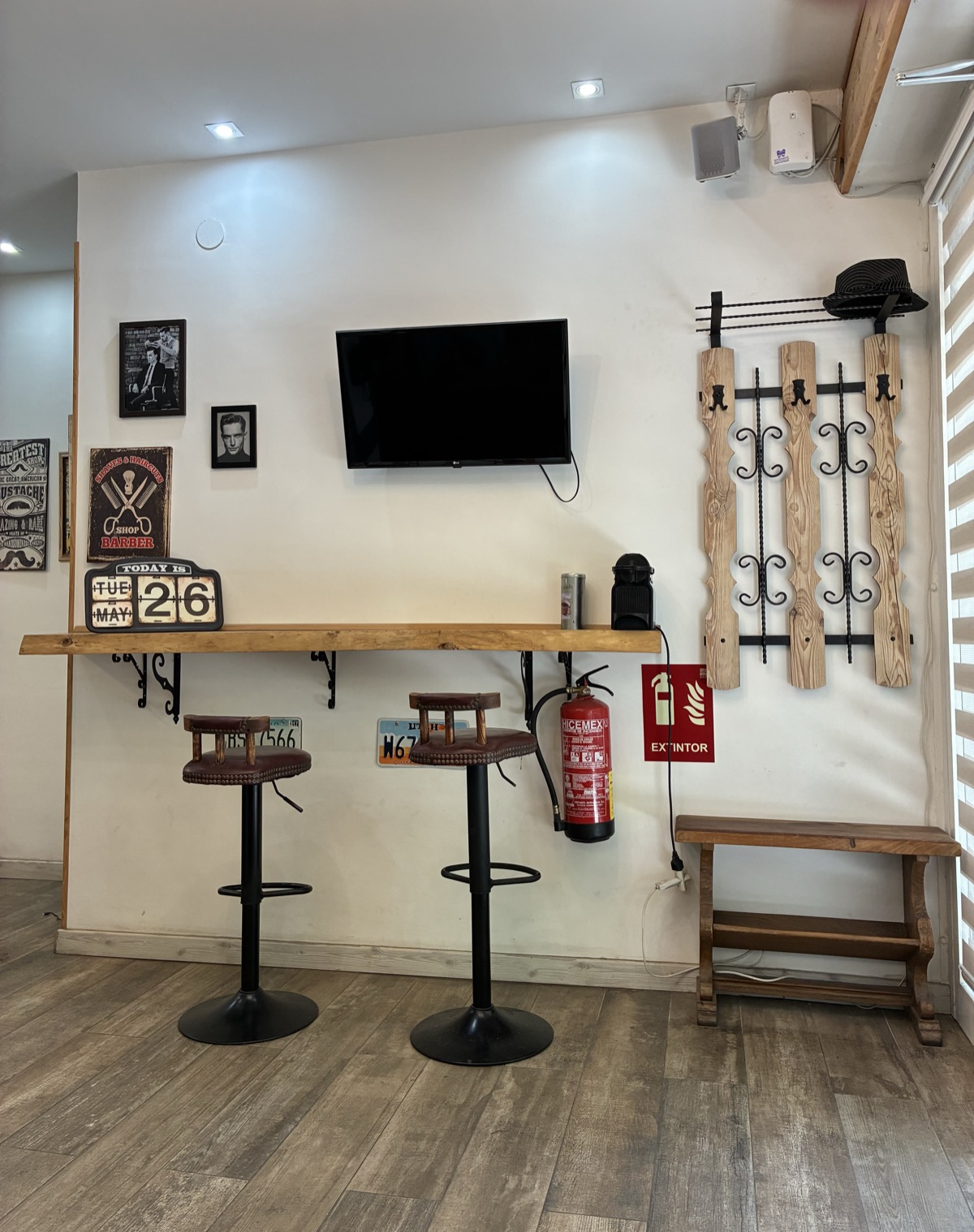Zona de espera con taburetes televisión y decoración vintage barbería El Clot Barcelona